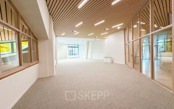 Spacious and modern office space at Bijlmerplein 888 in Amsterdam South East, featuring large windows and wooden ceiling accents, ideal for rent office space.