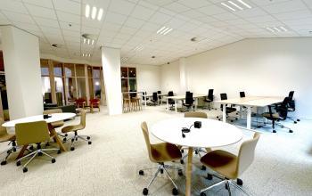 Spacious, well-lit office space with modern furnishings at Bijlmerplein 888, ideal for rent in Amsterdam South East. Features multiple desks and chairs, suitable for various business activities.