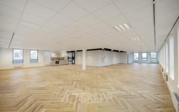 Spacious open floorplan office space rental at Hogehilweg 24, Amsterdam South East, featuring bright natural light, stylish wooden floors, and minimalist design ready for innovative work arrangements.