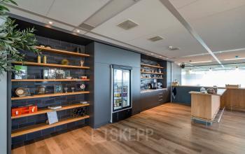 Modern pantry area in an office space located at De Entree 230-266, Amsterdam South East, featuring sleek shelves and a central counter, ideal for office space rental needs.