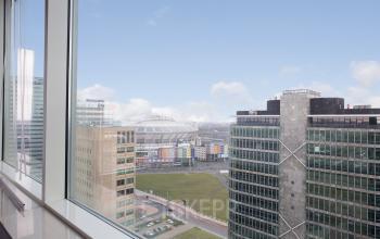 View from an office space in Amsterdam South East at De Entree 230-266, featuring modern high-rise buildings and the iconic stadium in the background.