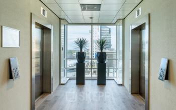 Modern office hallway at De Entree 230-266, Amsterdam South East, featuring sleek elevators and a bright view. Ideal for office space rental.