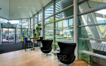 Bright and modern entrance area in the office located at De Entree 230-266, Amsterdam South East, featuring stylish seating and large windows. Ideal for greeting clients and colleagues.