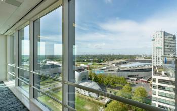 Large windowed office in Amsterdam South East with wide city views, ideal for office space rental, offering ample natural light and a dynamic environment.