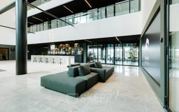 Modern office space rental at Herikerbergweg 288, Amsterdam South East, featuring a sleek interior with a seating area and bar stools, ideal for professionals looking to rent office space.