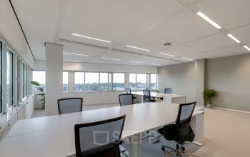 Spacious office to rent at Herikerbergweg 288, Amsterdam South East, featuring modern desks and chairs with large windows allowing ample natural light.