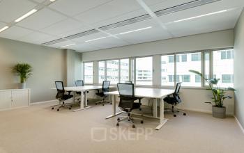 Bright office space at Herikerbergweg 288, Amsterdam South East, featuring large windows and furnished with desks and chairs, available for rent.