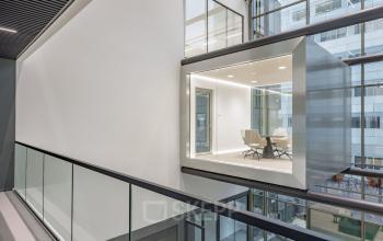 Modern office space rental at Herikerbergweg 288 in Amsterdam South East, featuring a glass-walled conference room with sleek chairs and a minimalist design.