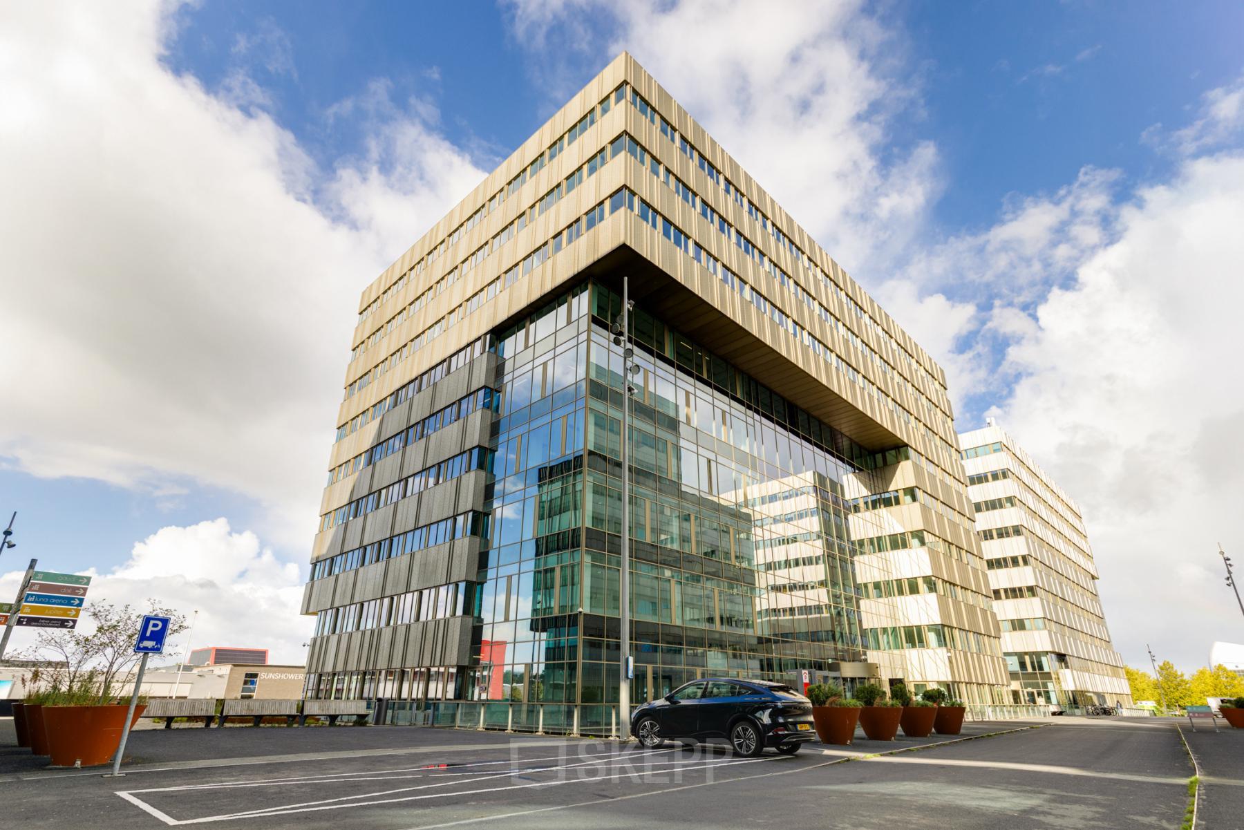 Modern office building at Herikerbergweg 288 in Amsterdam South East, featuring glass facade and available parking spaces for office space rental.