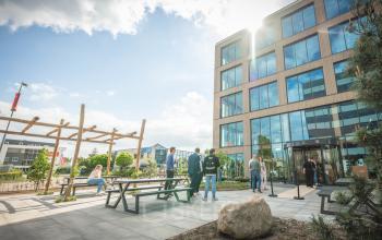 View of Luttenbergweg 8 in Amsterdam South East with people relaxing at picnic tables outside an office to rent.