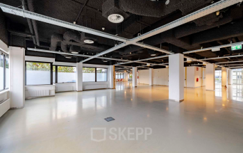 Spacious office interior with open floor plan and industrial ceiling design at Luttenbergweg 8 in Amsterdam South East, ideal for office space rental with ample natural light.