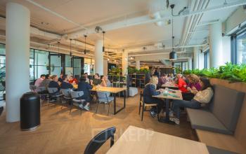 A bright office space at Luttenbergweg 8, Amsterdam South East, featuring modern furnishings with groups of people collaborating. Ideal for those seeking an engaging office space rental.