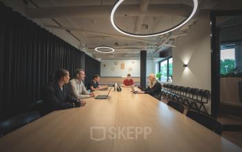 Individuals engaged in a meeting at a long table in a modern office space located at Luttenbergweg 8, Amsterdam South East, ideal for office space rental.