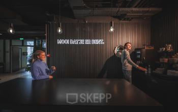 Two people enjoying a coffee break in a stylish, modern kitchen space at an office to rent in Amsterdam South East.
