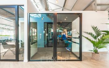 Modern office space at Luttenbergweg 8, Amsterdam South East with glass partitions and a person engaged in business activities, ideal for office space rental.