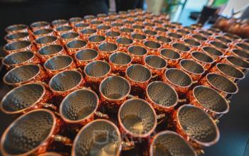 Copper cups are neatly arranged in rows on a table at Luttenbergweg 8, Amsterdam South East, showcasing a unique feature of the office space rental.
