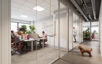 Office space for rent at Luttenbergweg 8, Amsterdam South East, featuring a modern workspace with glass partitions and natural light. Professionals engaging in meetings and discussions.