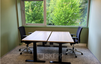 Bright office with two desks and chairs by a large window overlooking greenery, suitable for office space rental at Johan Cruijff Boulevard 89, Amsterdam South East.
