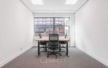 Bright office space rental at Paasheuvelweg 20, Amsterdam South East, featuring a large window and modern furnishings, perfect for collaborative work.