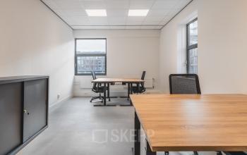 Bright office space with large windows at Paasheuvelweg 20, Amsterdam South East, featuring multiple desks and chairs, ideal for rent office space seeking natural light.