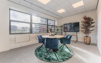 Bright office space with large windows at Paasheuvelweg 20, Amsterdam South East. Furnished with a round table and chairs, suitable for office space rental.