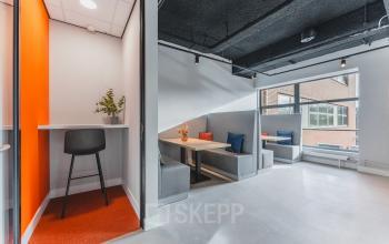 Modern office space at Paasheuvelweg 20, Amsterdam South East, with various seating options available for rent, including cozy booths and a high stool. Bright and inviting area for office space rental.