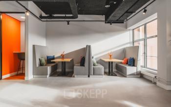 Modern office space rental at Paasheuvelweg 20 in Amsterdam South East, featuring cozy booth seating with cushions and a bright, inviting atmosphere.
