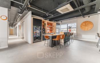 Modern office space at Paasheuvelweg 20 in Amsterdam South East with a furnished lounge area and vending machines, ideal for office space rental.