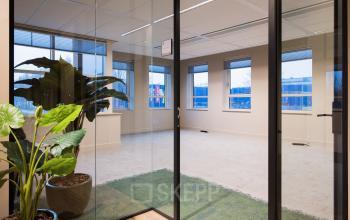 Bright office space at Hullenbergweg 109-135, Amsterdam South East, with large windows and lush plants. Perfect opportunity for office space rental with expansive workspaces.