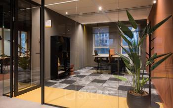 Modern office space for rent at Hullenbergweg 109-135 in Amsterdam South East, featuring glass walls, plants, and contemporary furnishings. Ideal for office space rental seekers.