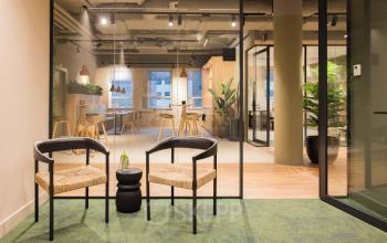 Modern office space in Amsterdam South East at Hullenbergweg 109-135, featuring a stylish interior with seating, glass partitions, and greenery, perfect for an office to rent.