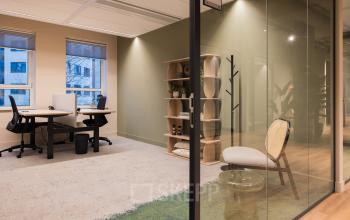 Modern furnished office space rental at Hullenbergweg 109-135, Amsterdam South East, featuring desks, chairs, and shelving with natural light filtering through the windows.