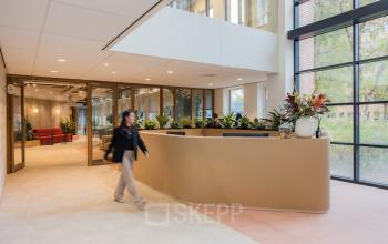 Modern office reception area at Hullenbergweg 109-135 in Amsterdam South East with a sleek reception desk and vibrant indoor plants. Ideal for those looking to rent office space in a stylish environment.