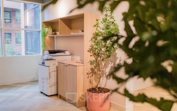Well-lit office interior at Hullenbergweg 109-135 featuring a multifunction printer and wooden shelving, available for office space rental.