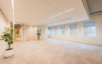 Bright, spacious office space with large windows and potted plants, ideal for office space rental in Amsterdam South East.