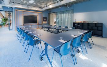 Bright conference room at Hullenbergweg 109-135, Amsterdam South East, featuring a large rectangular table with chairs and a presentation screen. Ideal for office space rental.