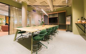 Bright and airy conference room at Hullenbergweg 109-135, Amsterdam South East, ideal for office space rental with long tables and green chairs.