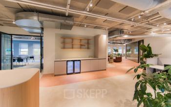 Modern office space at Hullenbergweg 109-135, Amsterdam South East, featuring stylish interiors with light flooring, a kitchenette, and contemporary furnishings, ideal for office space rental.