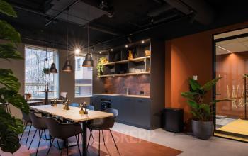 Modern office space in Amsterdam South East at Hullenbergweg 109-135, featuring a stylish furnished interior with a communal workspace and kitchenette for office space rental activities.