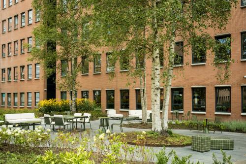 Outdoor seating area with tables and chairs surrounded by greenery at Hullenbergweg 109-135, perfect for office space rental in Amsterdam South East.