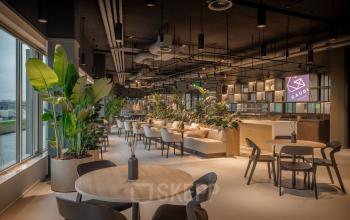 Spacious and modern furnished office space for rent at Herikerbergweg 290, Amsterdam South East, featuring stylish seating and lush greenery, ideal for collaborative workspaces.