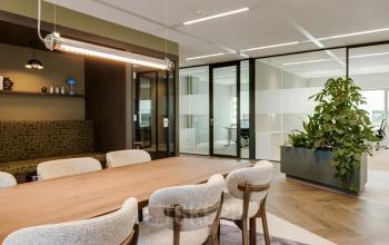 Furnished office space at Herikerbergweg 290 in Amsterdam South East with a large table, chairs, and indoor plants, ideal for those looking to rent office space.
