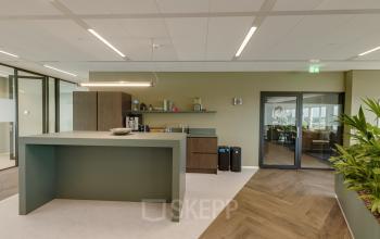 Furnished office space for rent with modern design at Herikerbergweg 290, Amsterdam South East, featuring a central island, plants, and contemporary lighting.