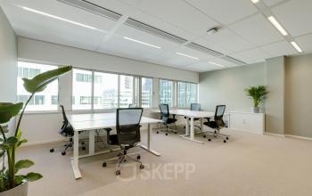 Bright office space for rent at Herikerbergweg 290, Amsterdam South East, featuring modern desks and chairs, with views of surrounding buildings.