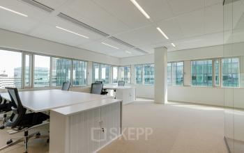 Bright office space rental at Herikerbergweg 290, Amsterdam South East, featuring modern desks and chairs in a light-filled room.