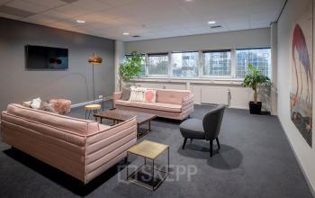 Comfortable lounge area with modern sofas and armchairs, large windows, and indoor plants at Hogehilweg 8, Amsterdam South East, Amsterdam. Ideal for office space rental.