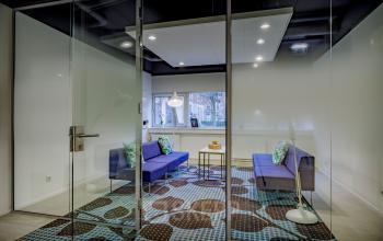 Modern office space rental at Hogehilweg 8, Amsterdam South East, featuring glass walls, stylish furniture, and ample lighting.
