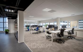 Spacious office to rent at Hogehilweg 8, Amsterdam South East, featuring multiple desks with chairs and computer monitors, large windows providing ample natural light.