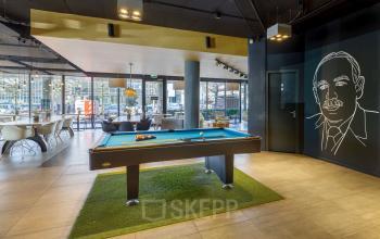 Interior of the office space located at Hogehilweg 8, Amsterdam South East, featuring a pool table, seating areas, and large windows offering natural light.
