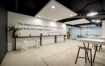 Modern office space to rent at Hogehilweg 8, Amsterdam South East with high ceilings, stylish decor, and comfortable seating areas.